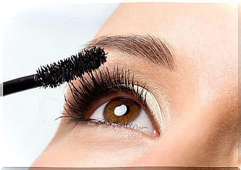 Woman applies mascara on lashes