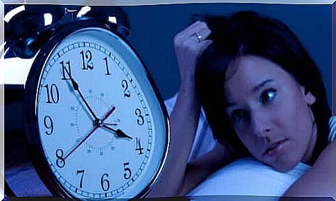 A woman looks desperately at the alarm clock